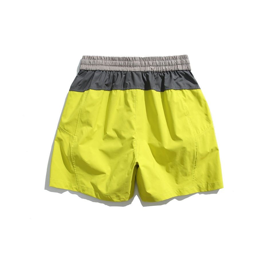 Back view of neon yellow shorts with a charcoal upper panel and light gray elastic waistband.