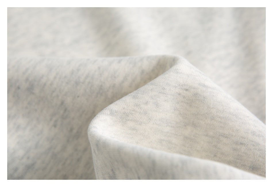 Close-up of light gray heathered garment fabric, highlighting its surface and folded edge.
