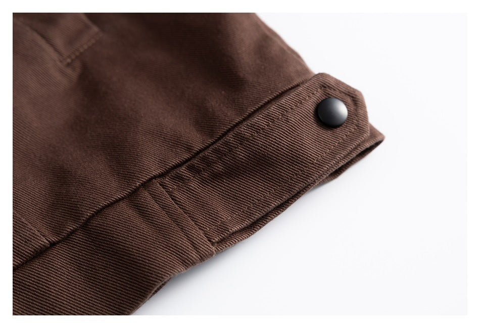 Close-up of a dark brown jacket cuff tab fastened with a black snap.