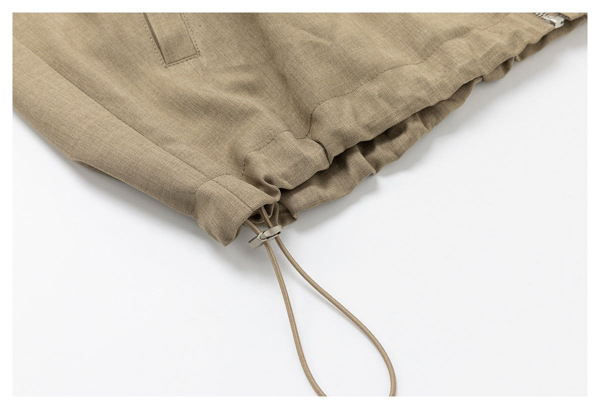 Close-up of the taupe jacket's gathered hem and adjustable drawstring toggle.