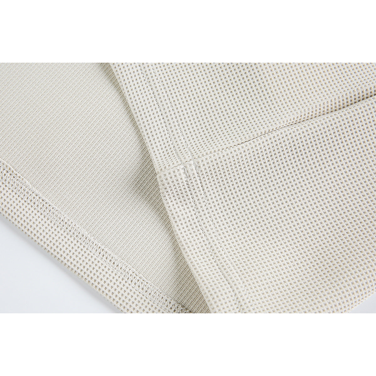Close-up of ivory waffle-knit fabric showing an interior seam and overlock stitching.