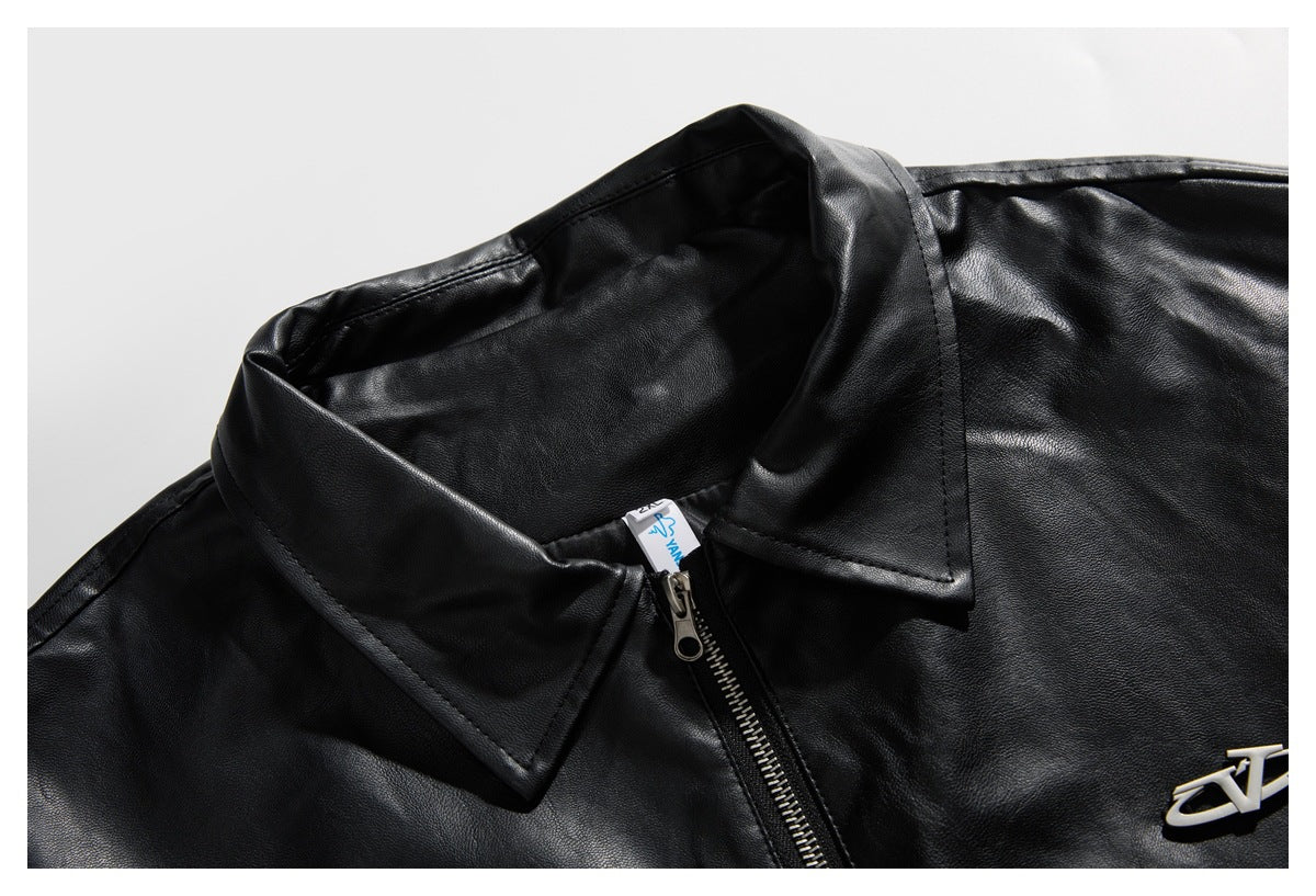 Close-up of a black jacket's pointed collar, front zipper, and silver chest emblem.
