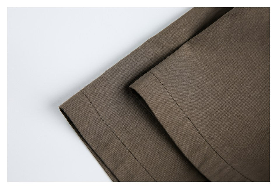 Close-up of two overlapping brown garment hems with visible stitching.