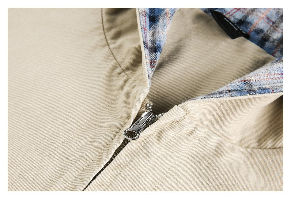 Close-up of a beige jacket's metal front zipper beside the plaid-lined hood.