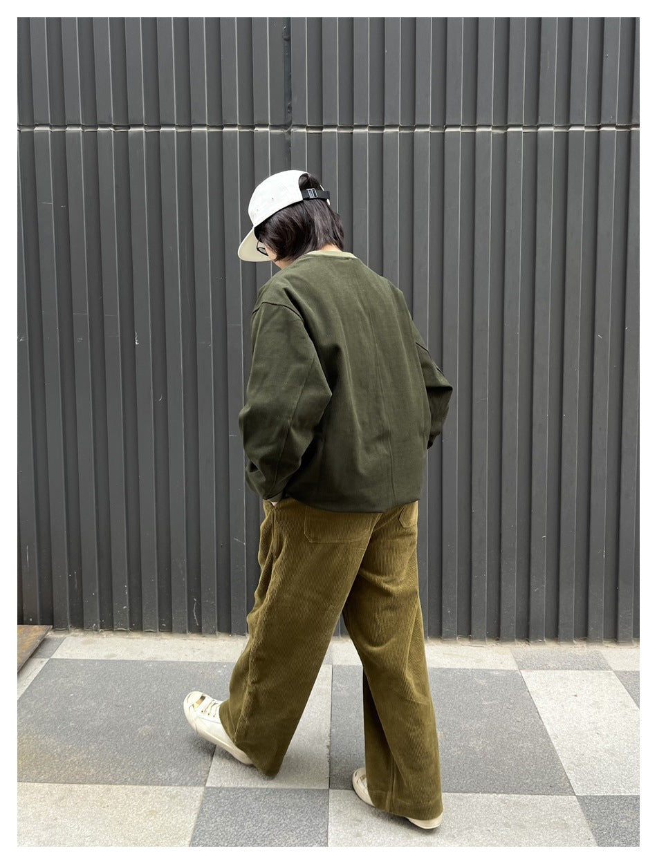Person seen from behind wearing a green sweatshirt with olive corduroy pants and a white cap