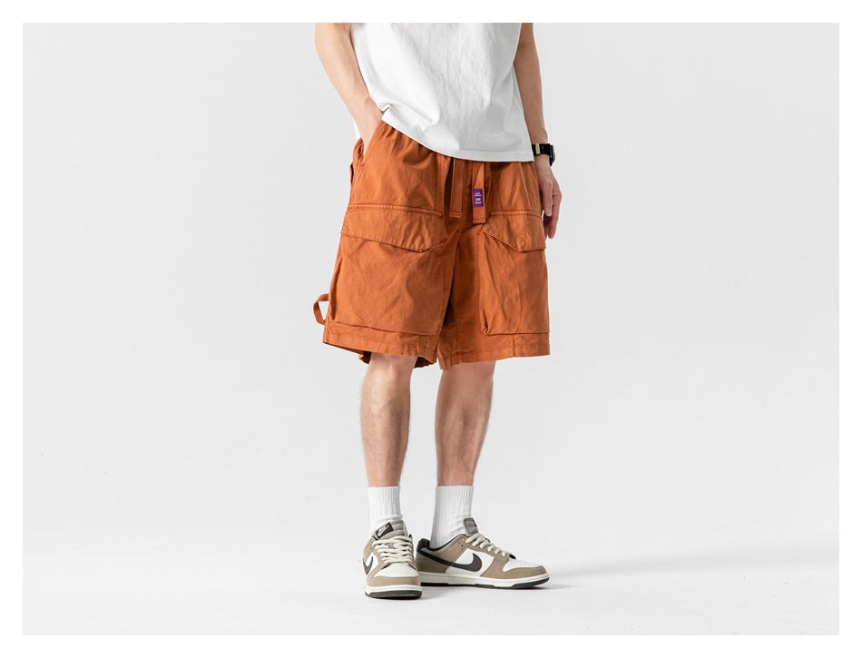 Model wearing caramel cargo shorts with a white tee and sneakers, angled view showing side pocket and strap