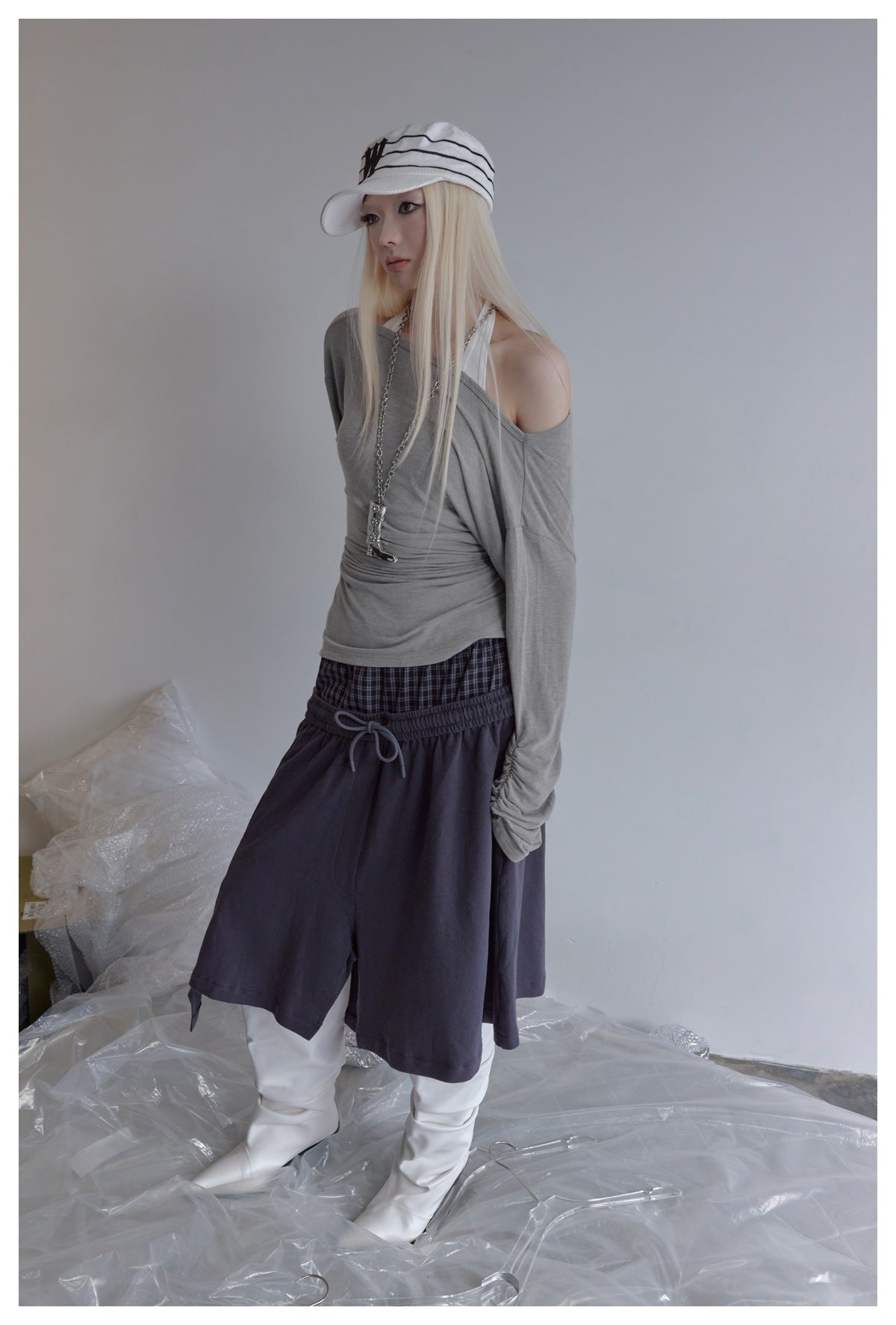 Model wearing a gray off-shoulder long-sleeve top with gathered sleeves and dark layered bottoms.
