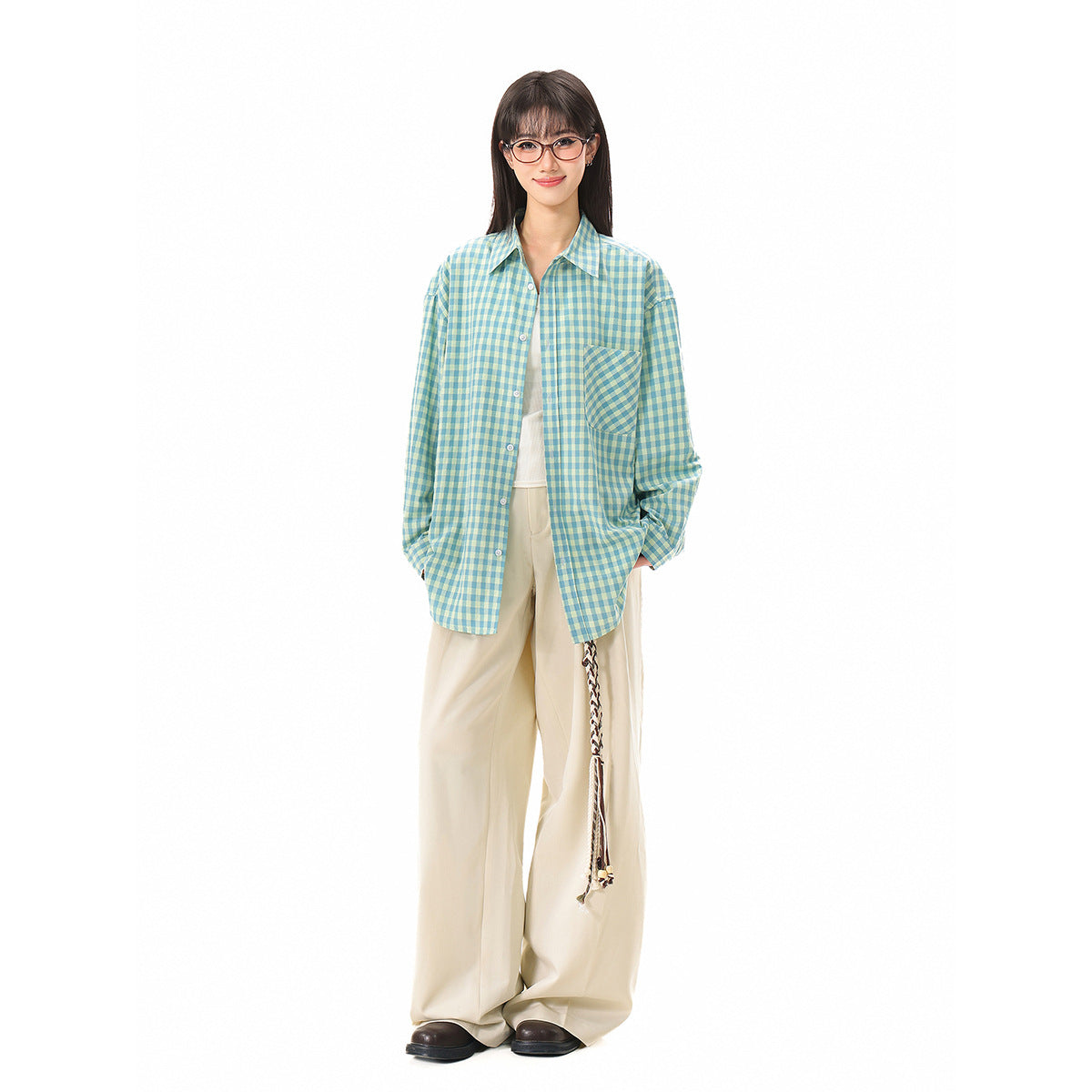 Full-length model wearing an oversized teal and pale yellow gingham shirt with a chest pocket and wide cream trousers.