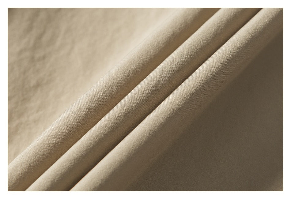 Close-up of light tan fabric draped in soft folds, showing its surface texture.