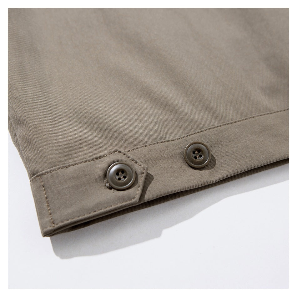 Close-up of a taupe garment hem with a buttoned adjustment tab.