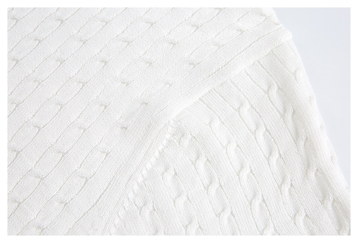 Close-up of an ivory knit garment with a raised geometric stitch pattern.