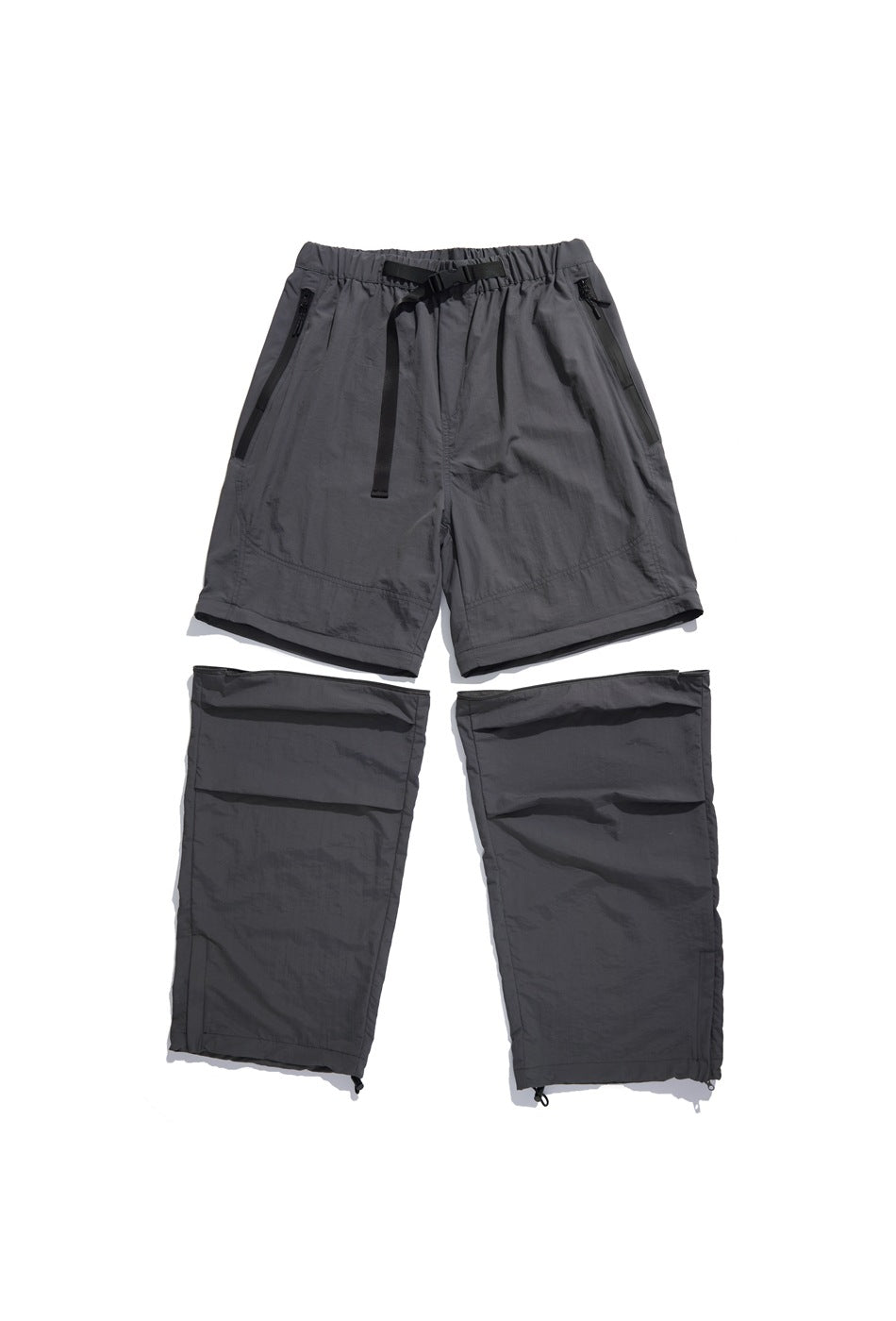 Gray convertible pants laid flat with the lower legs detached, showing the belt, zip pockets and hem drawcords