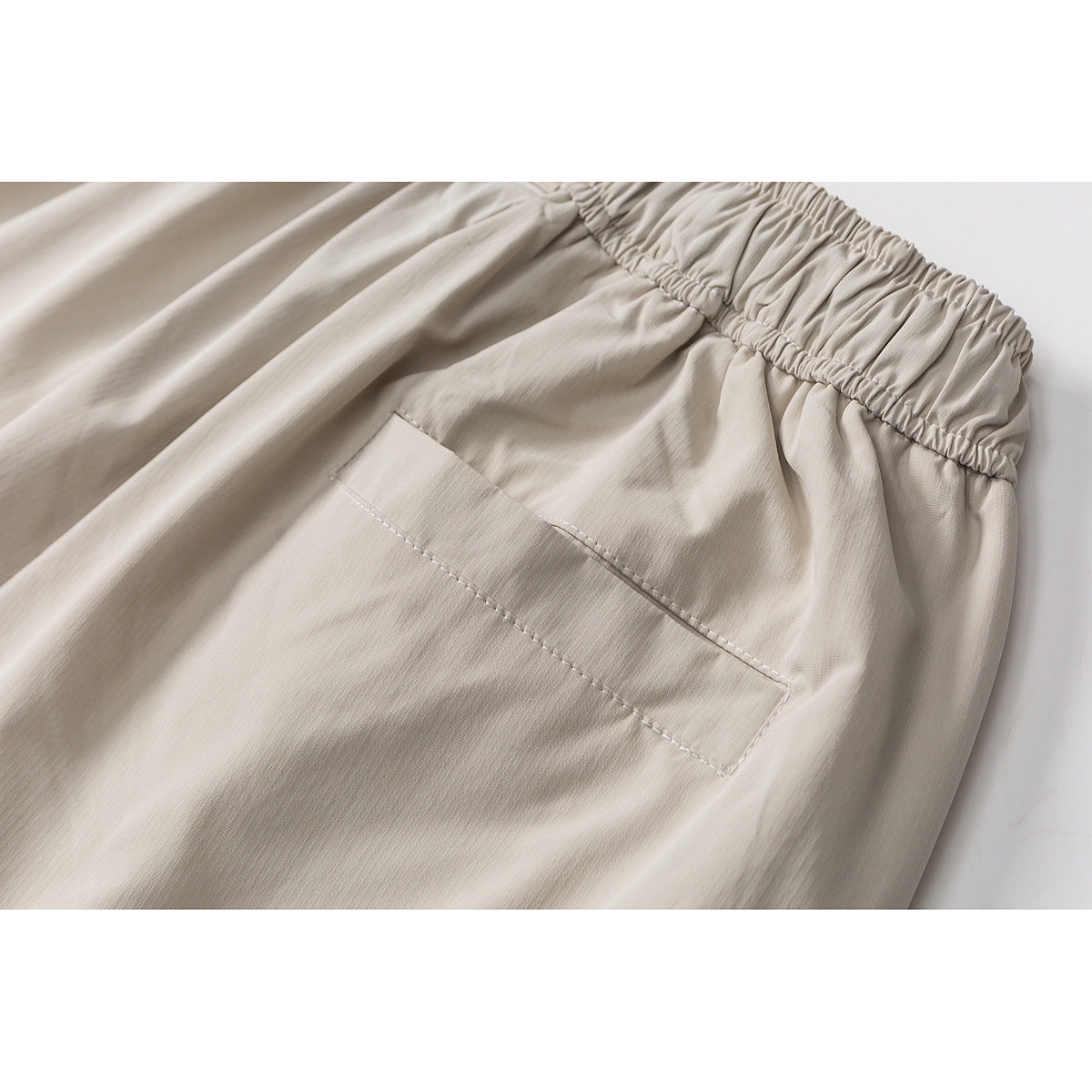 Close-up of light beige shorts showing the gathered waistband and a stitched rear pocket.