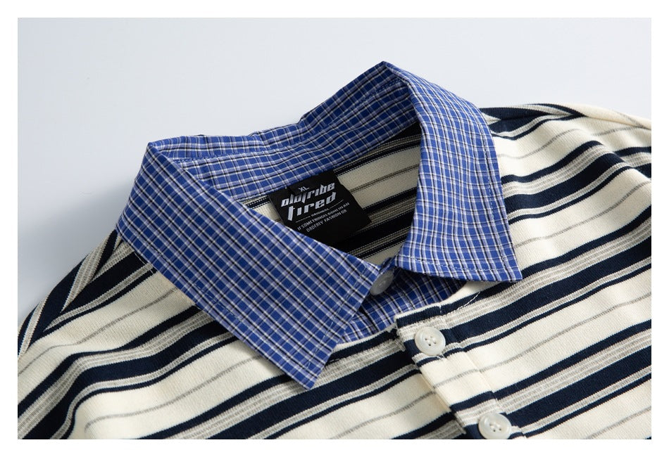 Close-up of a cream shirt with navy and gray stripes, a blue plaid collar, and white buttons.