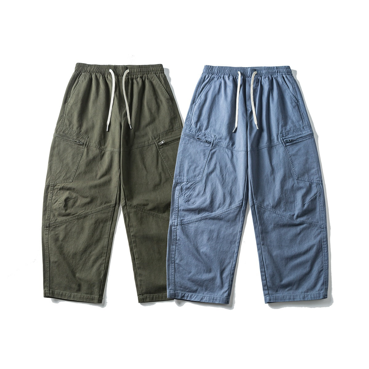 Front view of loose cargo pants in olive and blue, with elastic waistbands, white drawstrings, and large pockets.