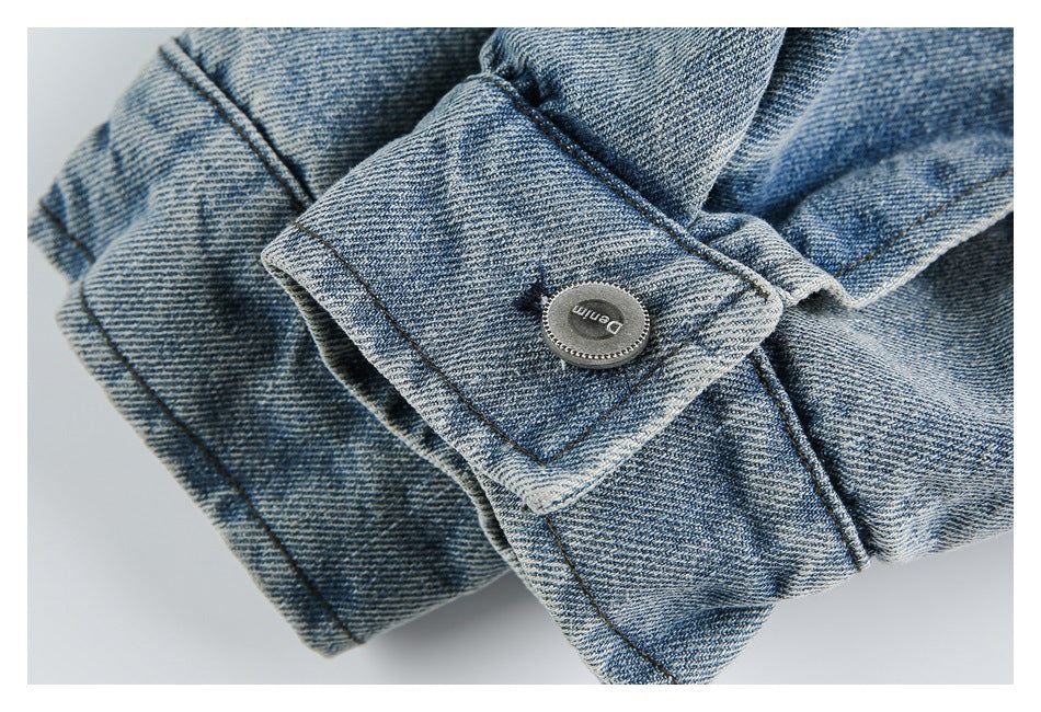 Close-up of a blue denim jacket cuff with a round metal button marked “Denim.”