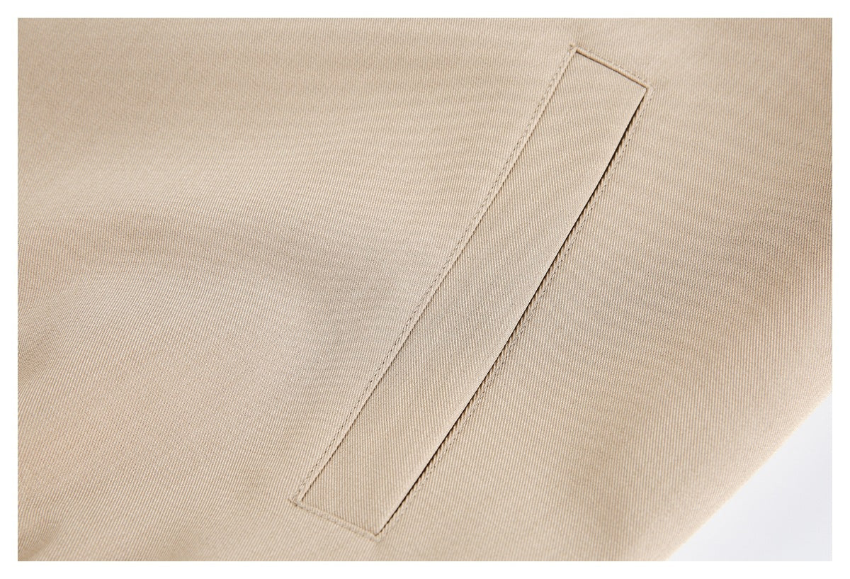 Close-up of a narrow welt pocket on the beige jacket.