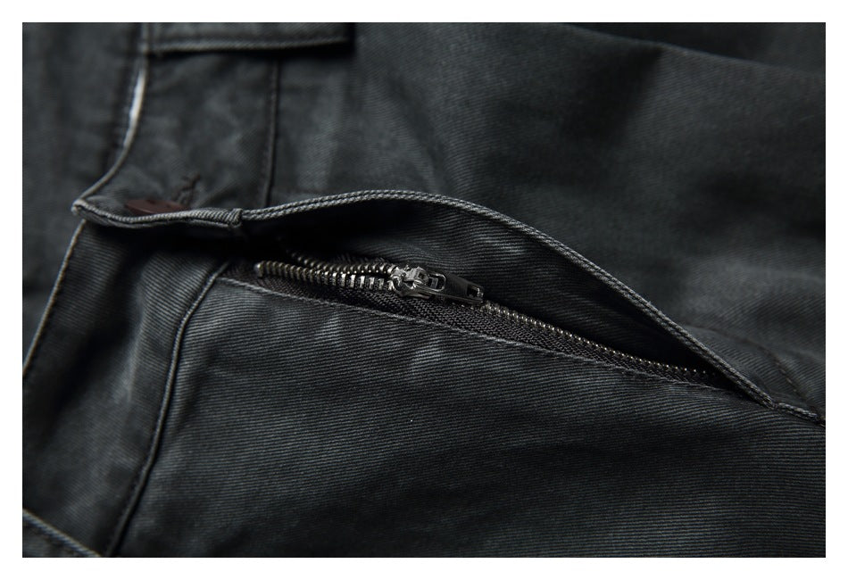 Close-up of charcoal pants with the fly open, revealing a dark metal zipper.