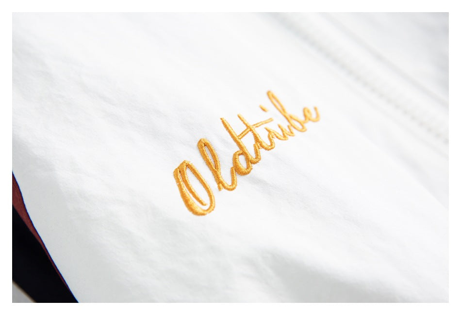 Close-up of gold cursive embroidery on white fabric.