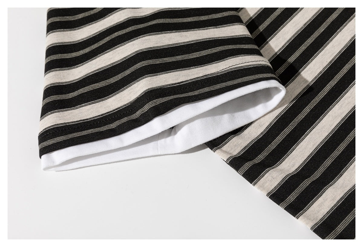 Close-up of a folded sleeve edge on a black and cream striped shirt, showing white inner trim.