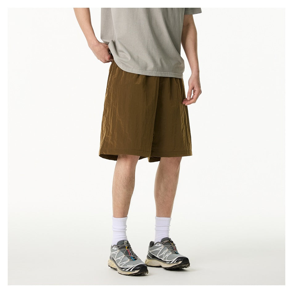 Rear view of a model wearing loose olive-brown knee-length shorts with a plain back and no visible pockets.
