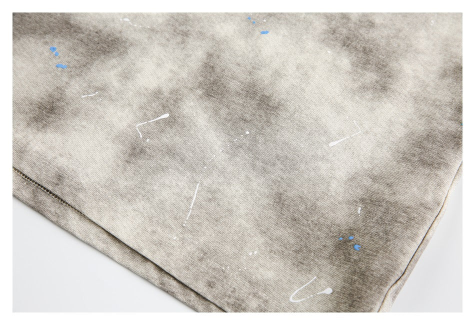 Close-up of the beige-gray shirt's mottled fabric and scattered white and blue marks near the hem.