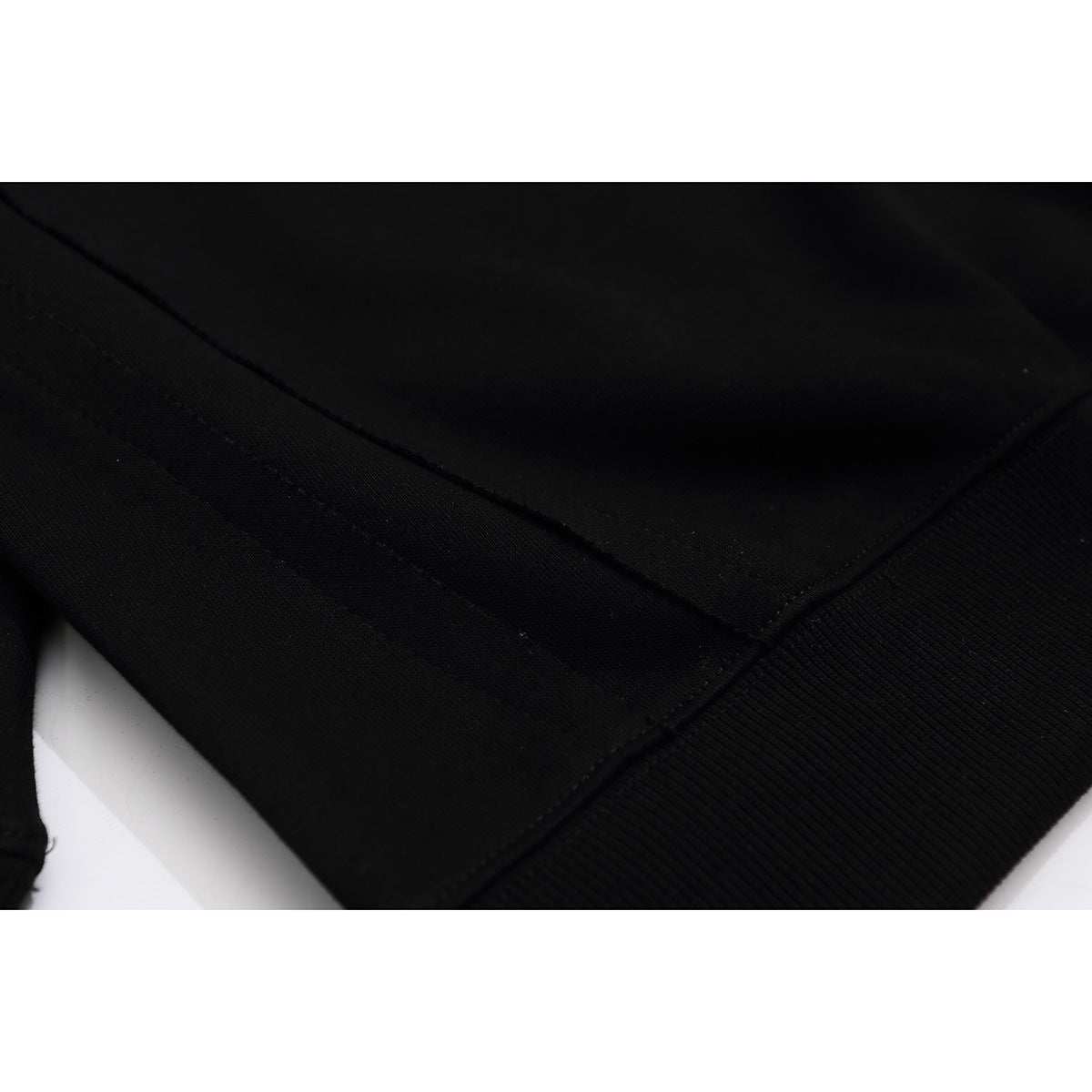 Close-up of the black sweatshirt’s ribbed bottom hem and stitching.