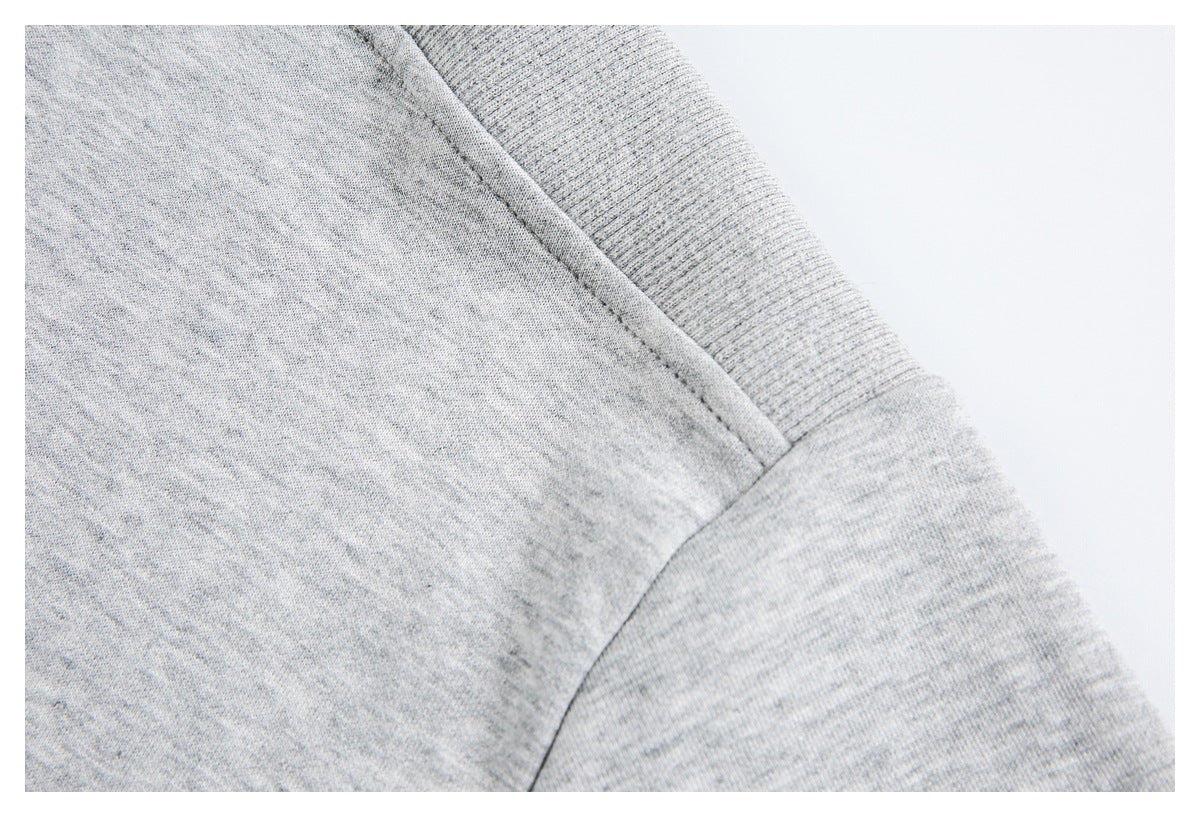 Close-up of a light heather-gray shirt's shoulder seam and sleeve construction.