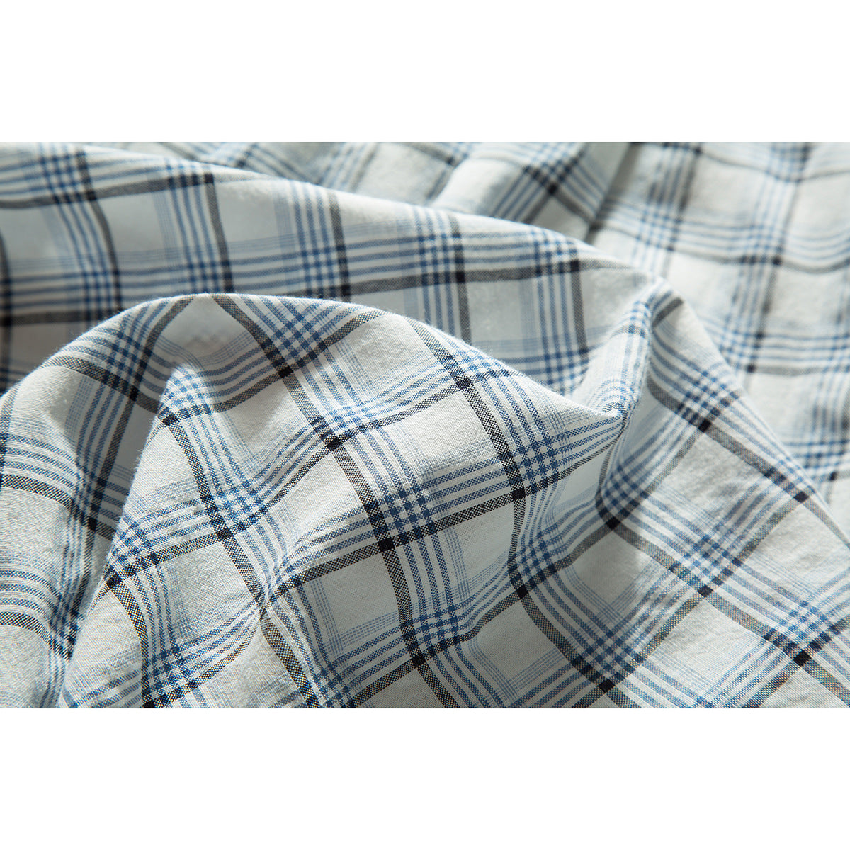 Close-up of draped white shirt fabric in a blue and charcoal plaid pattern.