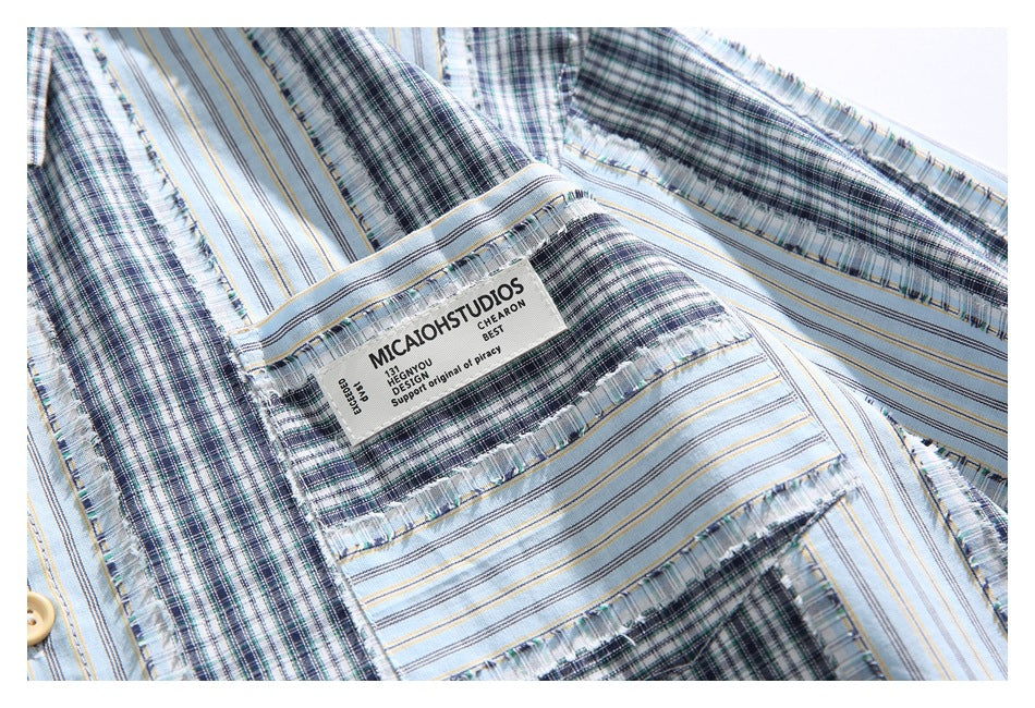 Close-up of a chest pocket on the patterned shirt, showing a sewn English-text label and fringed seams.