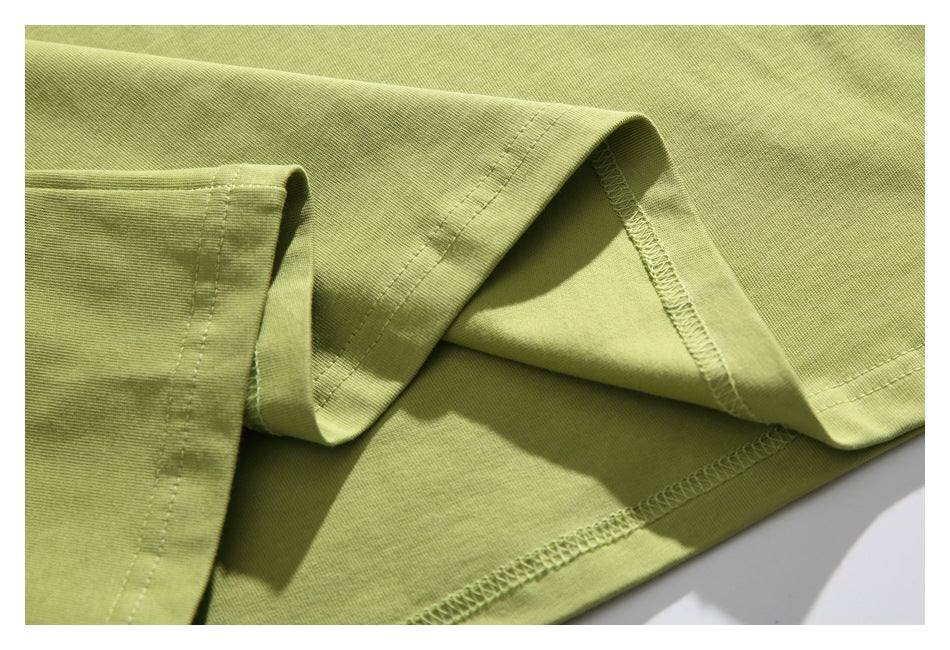 Close-up of the light olive-green T-shirt's sleeve and hem stitching, including the inside overlock seams.