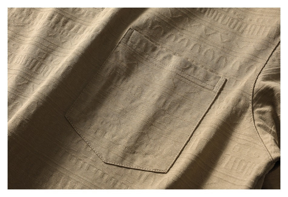 Close-up of a tan shirt with a large stitched patch pocket and subtle tonal woven patterns.