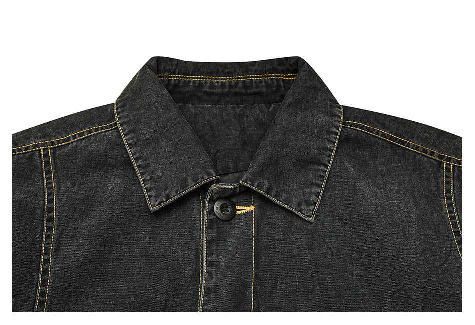 Close-up of a black denim jacket collar and upper front with yellow contrast stitching and a dark button.
