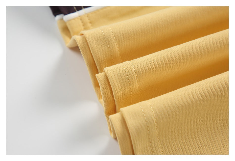 Close-up of several pale yellow garment hems with visible stitching and a dark panel with white piping.