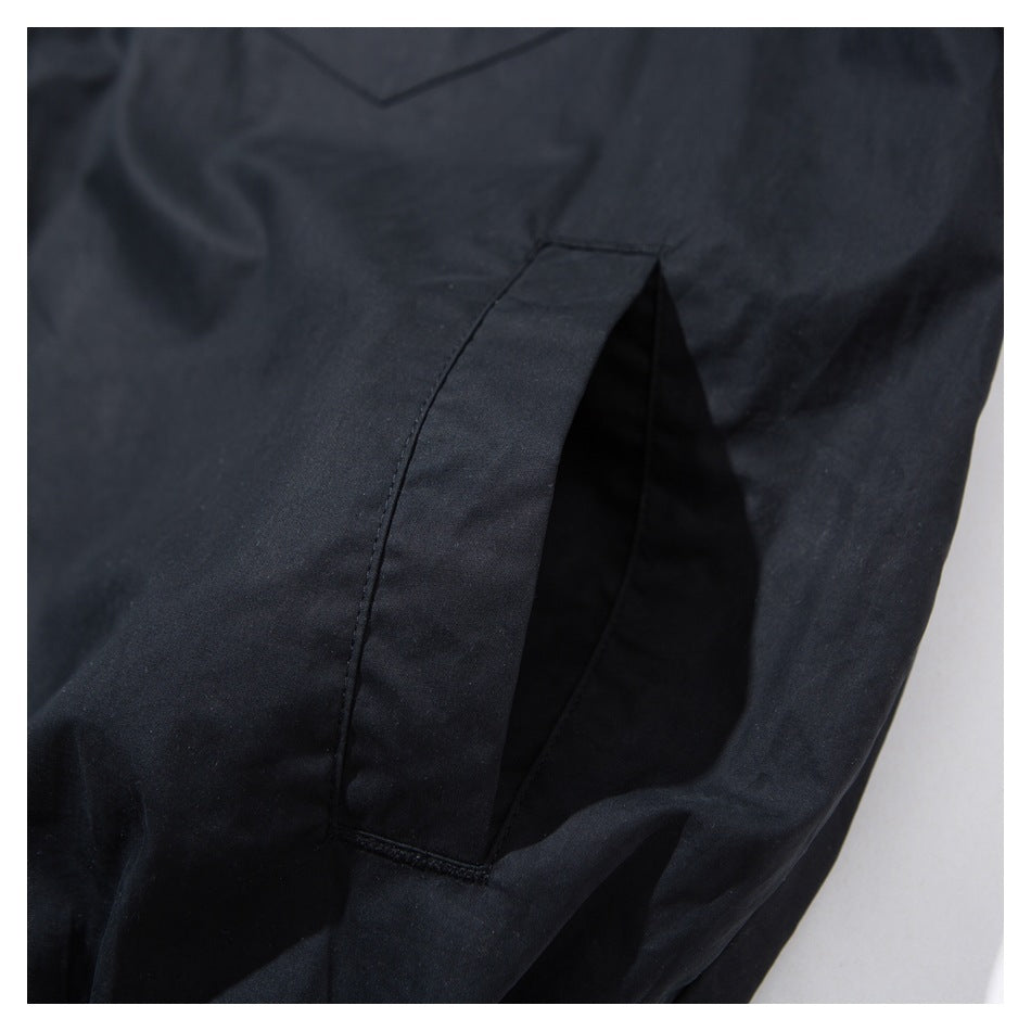 Close-up of a black garment showing a deep side pocket opening and its stitched edge.