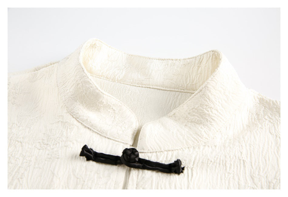 Close-up of the ivory top’s standing collar and a black knotted frog closure.