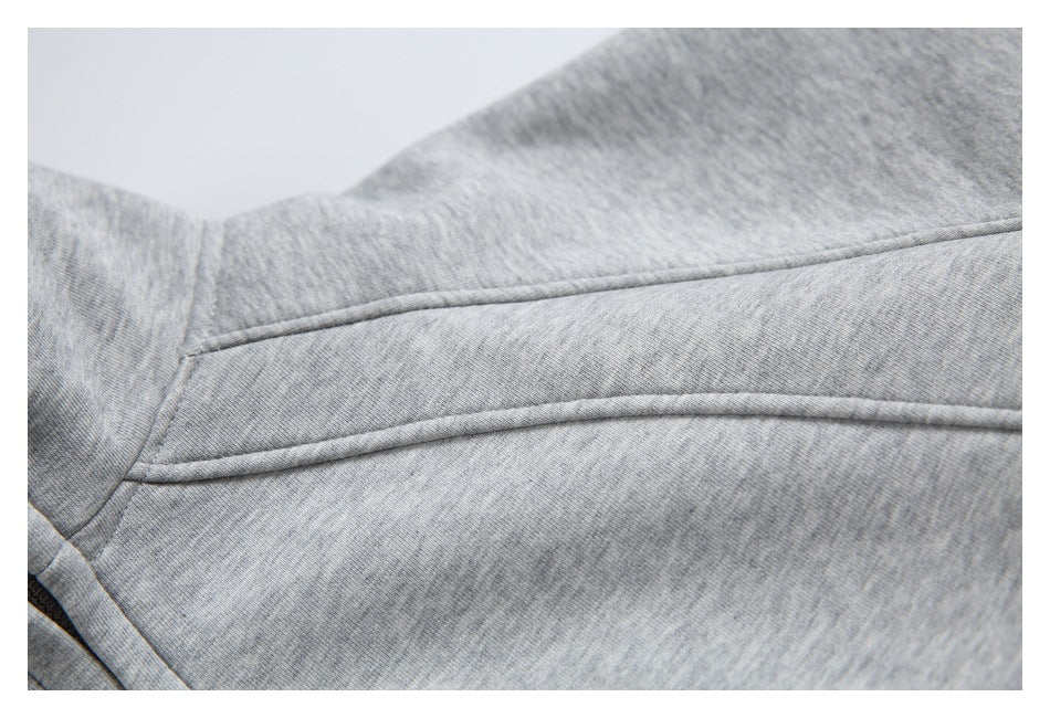 Close-up of gray heather fabric with curved piped seams and a stitched panel.