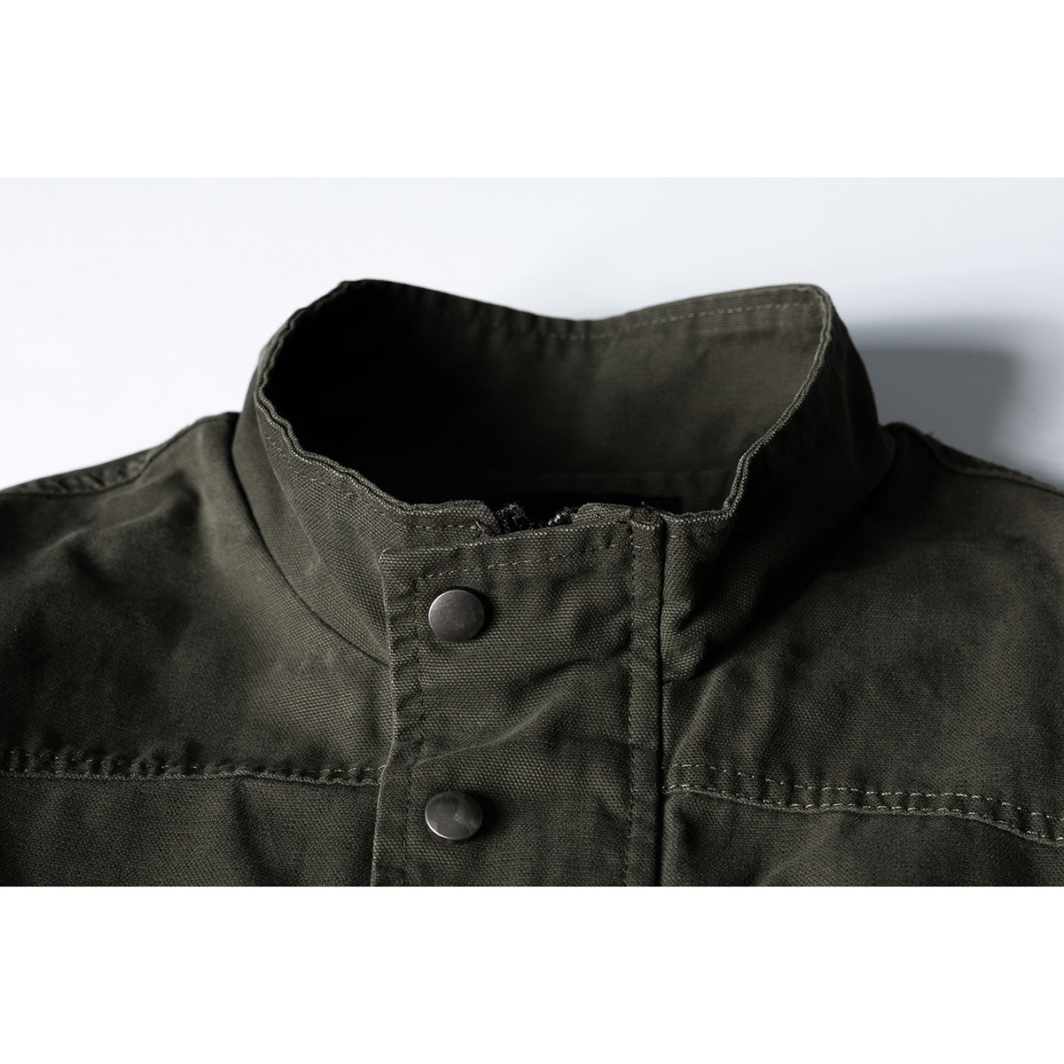 Close-up of an olive drab jacket’s stand collar, snap-button placket and shoulder seams.