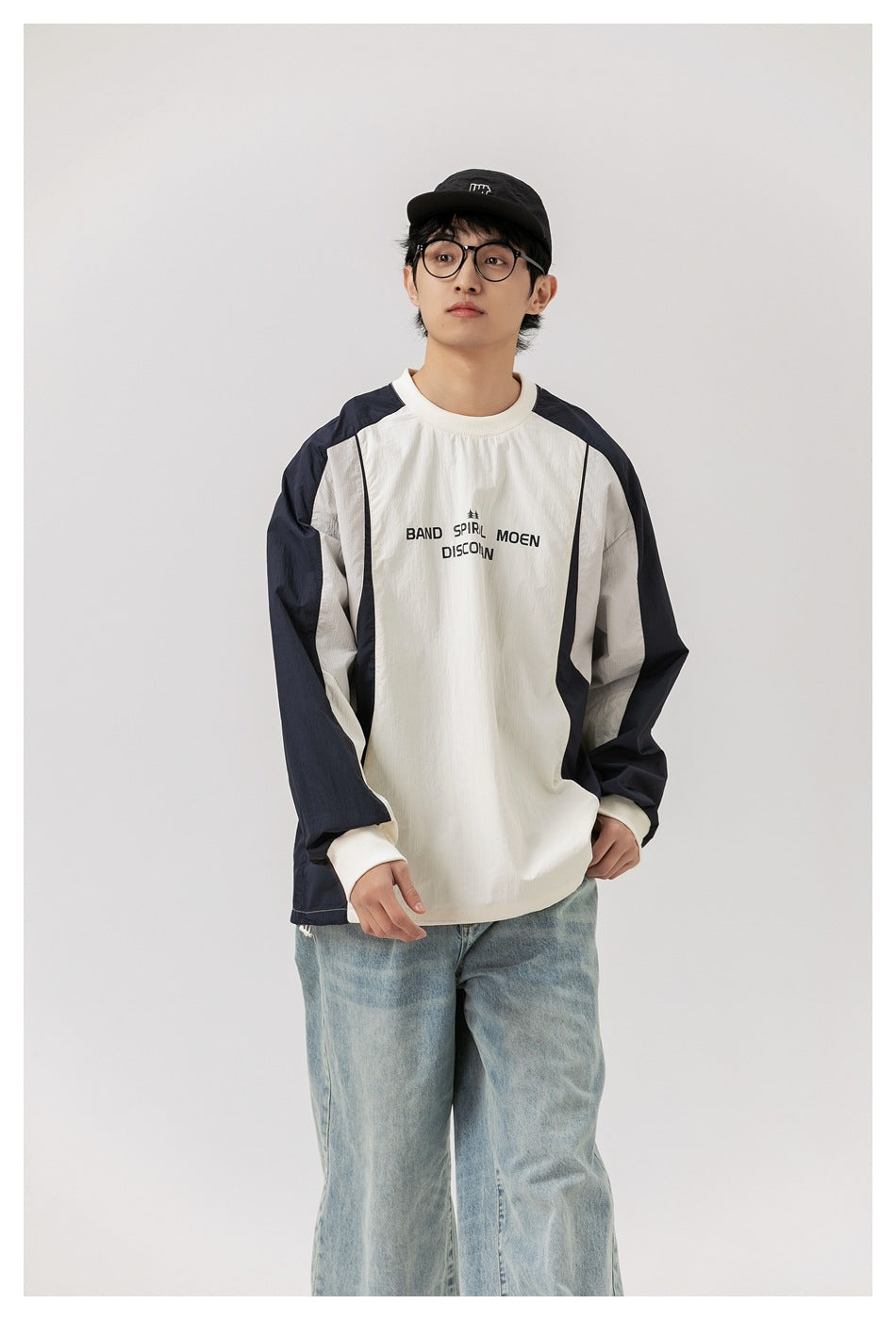 Closer front view of a model wearing an ivory top with navy sleeves and side panels and black chest lettering.