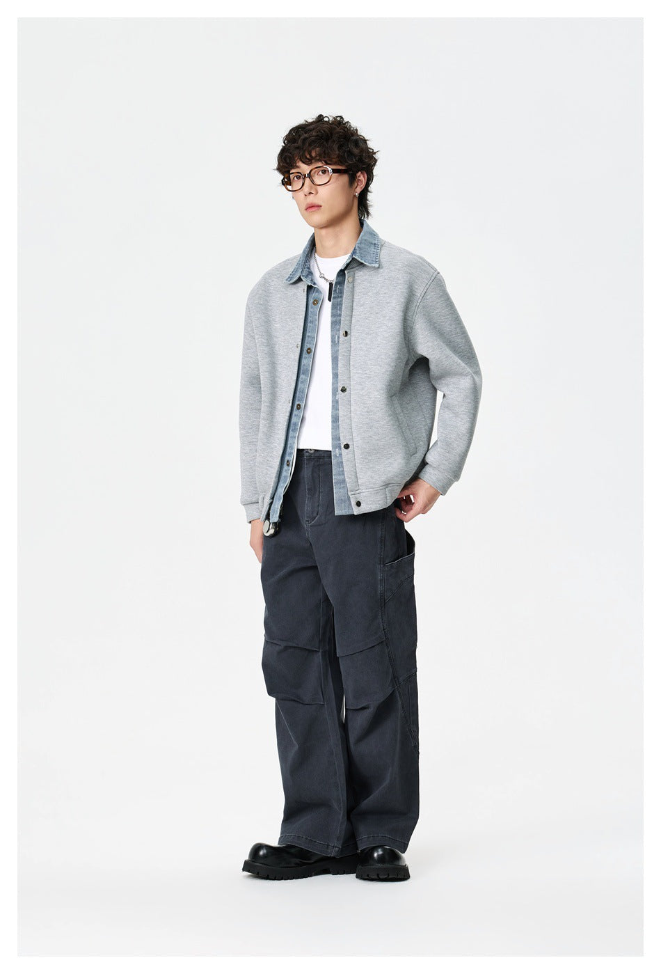 Model wearing a light gray snap-front jacket with a blue denim collar and placket, paired with dark cargo pants.