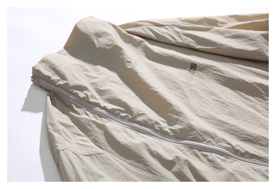 Close-up of beige jacket fabric and a curved zipper running along a panel seam.