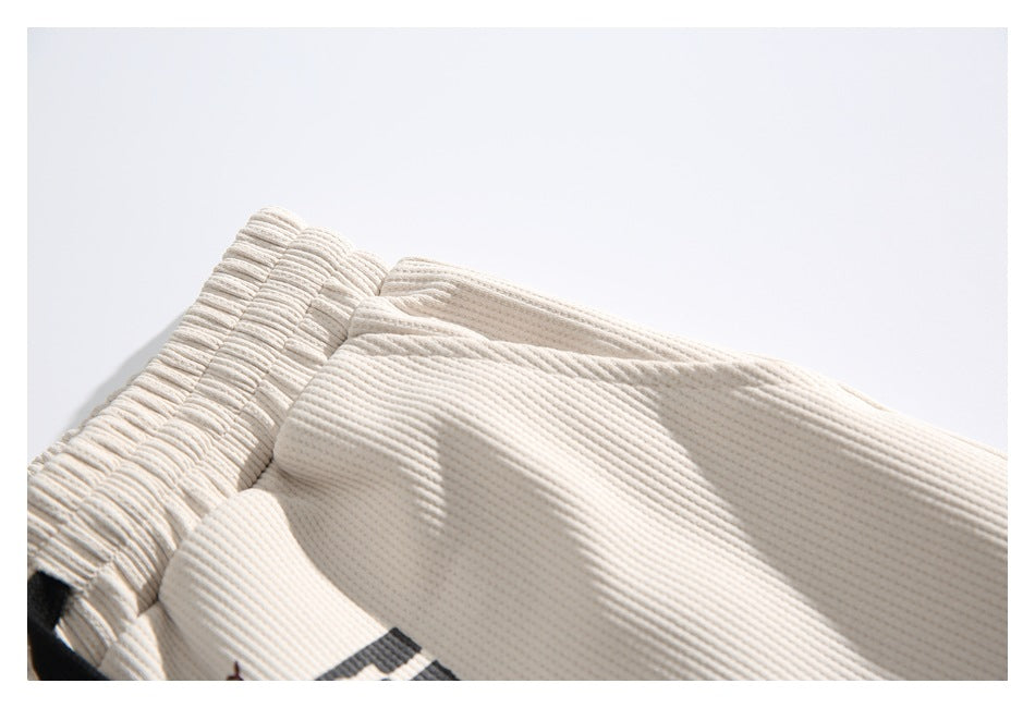 Close-up showing the gathered waistband and ribbed texture of ivory shorts.