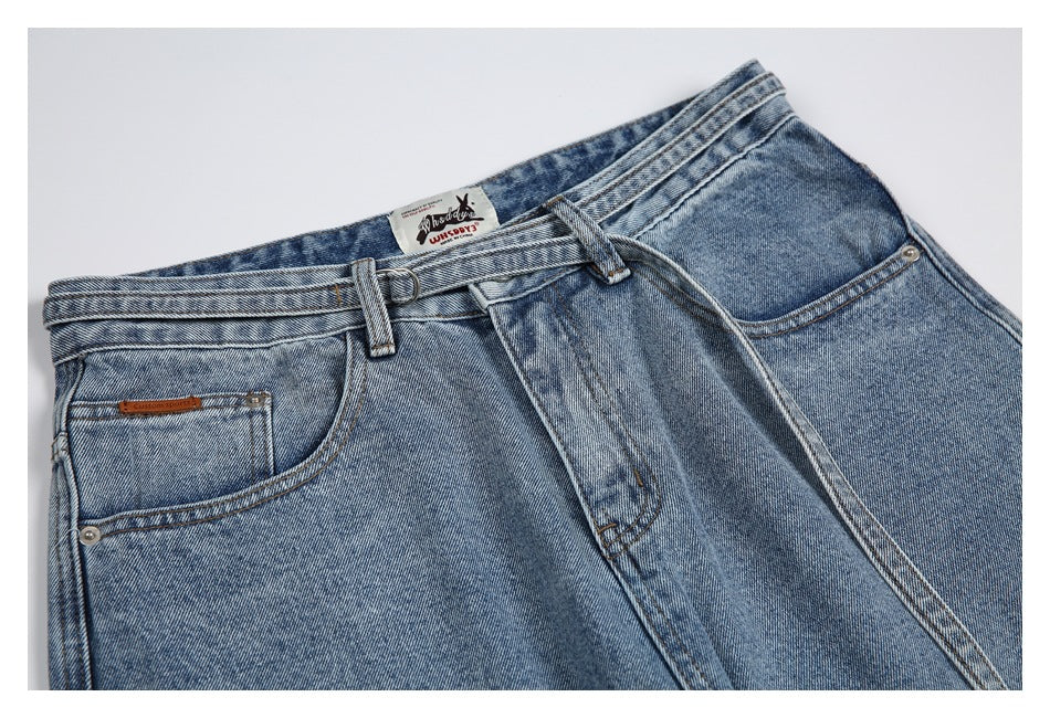 Close-up of light-wash jeans showing the waistband, belt loops, front pockets, button, and labels.