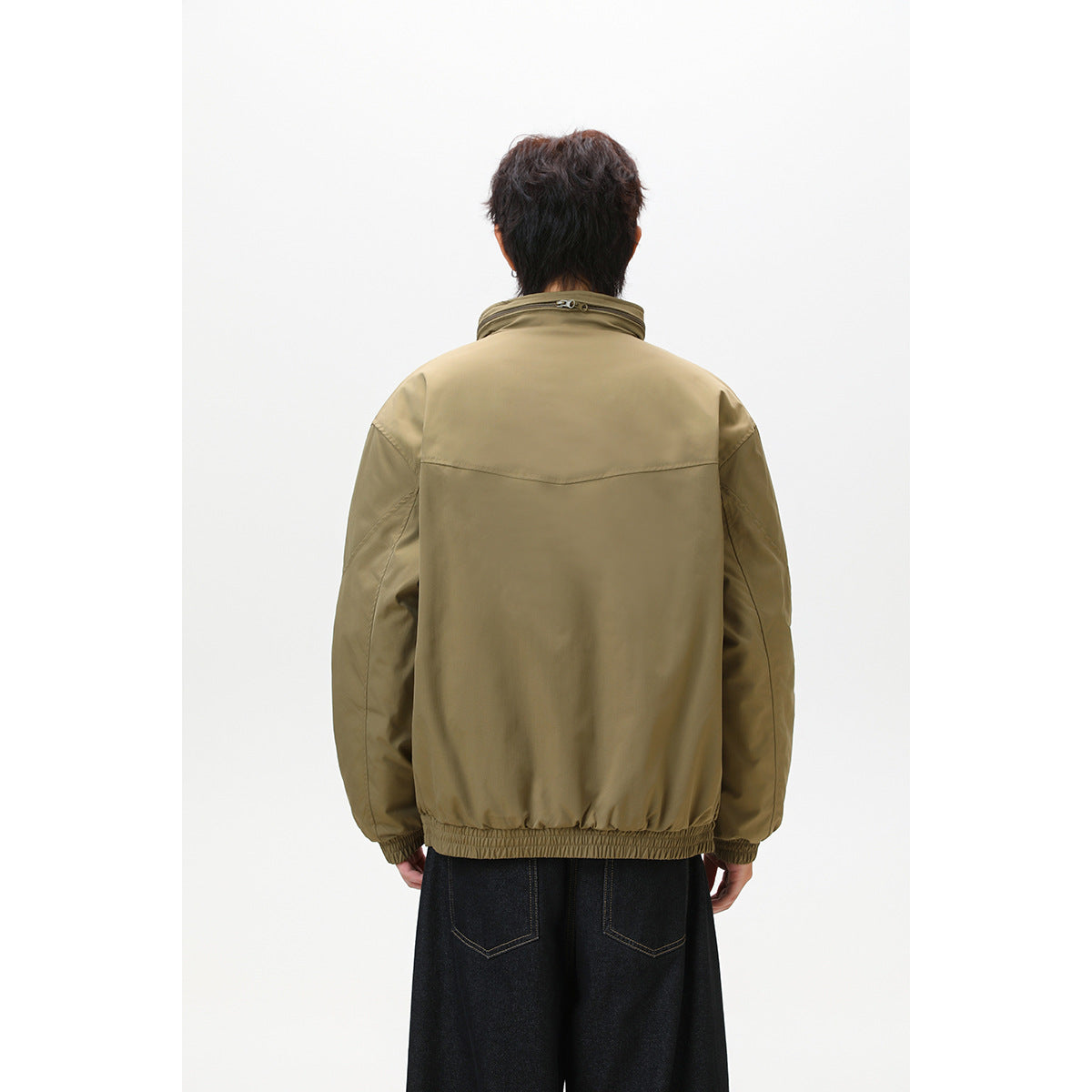 Back view of a model wearing an olive-brown jacket with a raised collar and gathered hem.