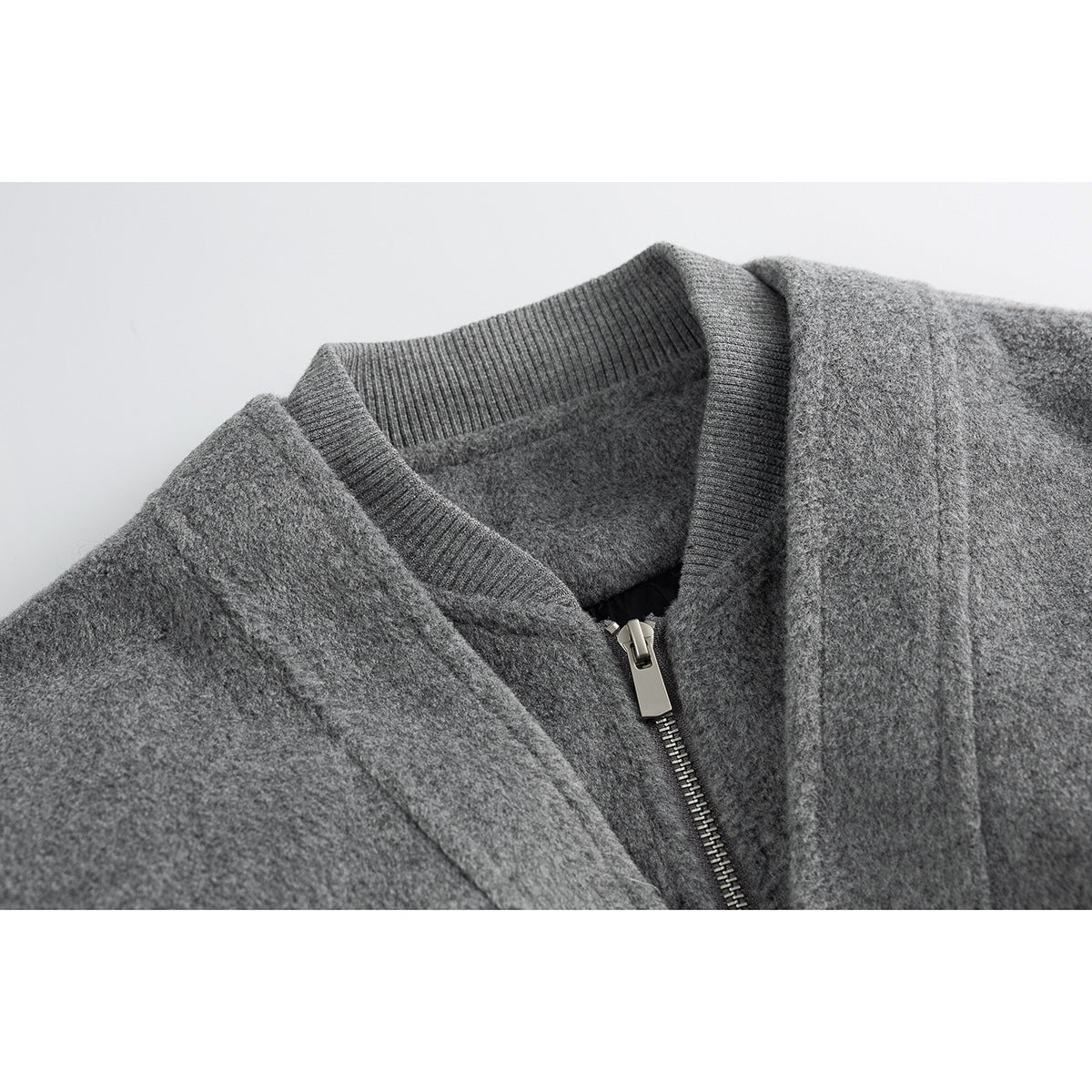 Close-up of a gray jacket's ribbed collar and silver front zipper.