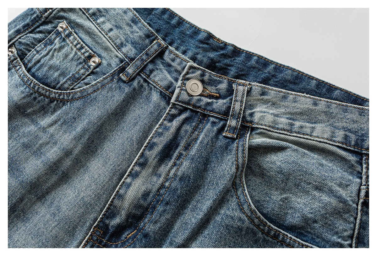 Close-up of faded blue jeans at the front waist, showing the button, belt loops and pockets.