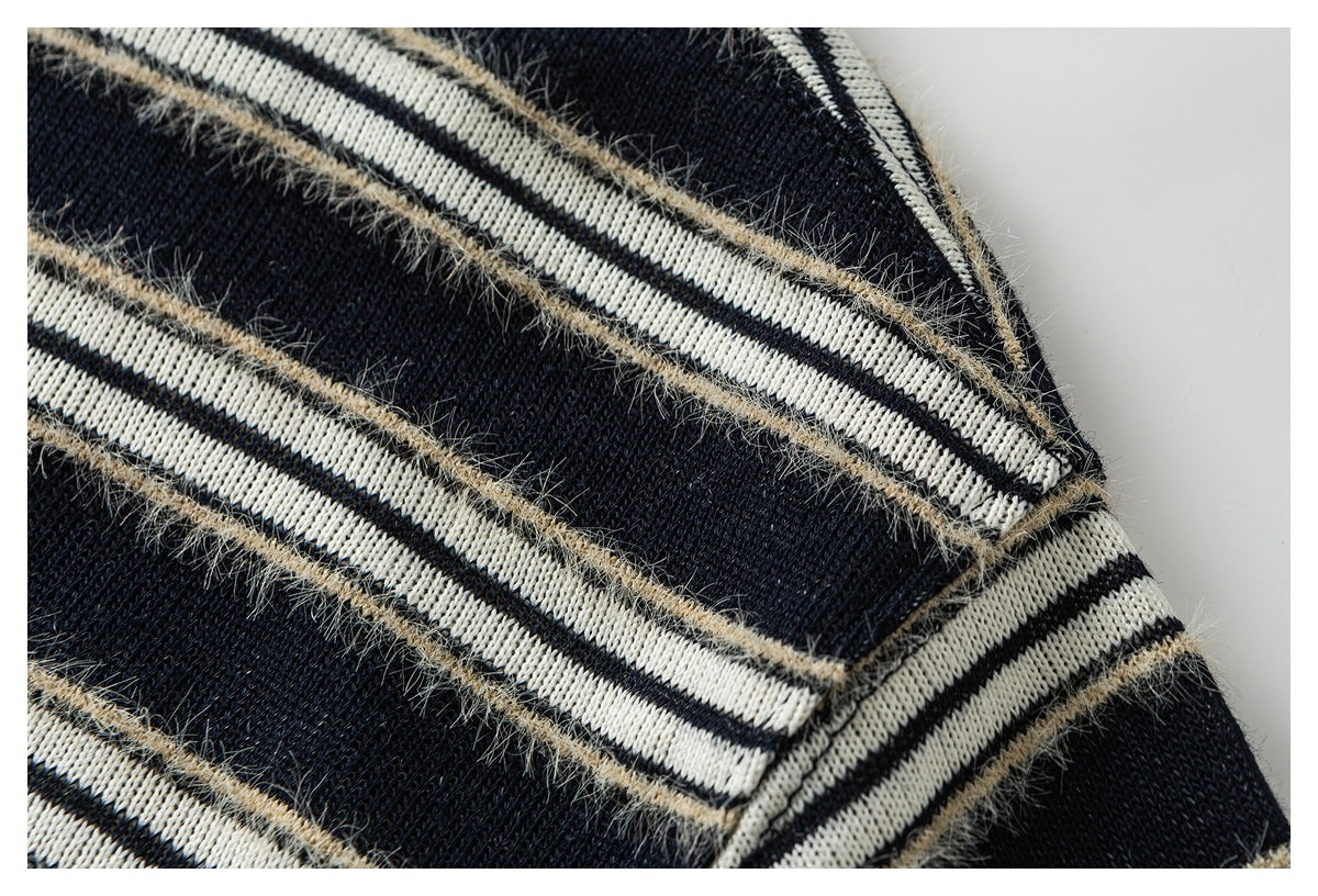 Close-up of black knit fabric with cream stripes and fuzzy tan yarn accents.