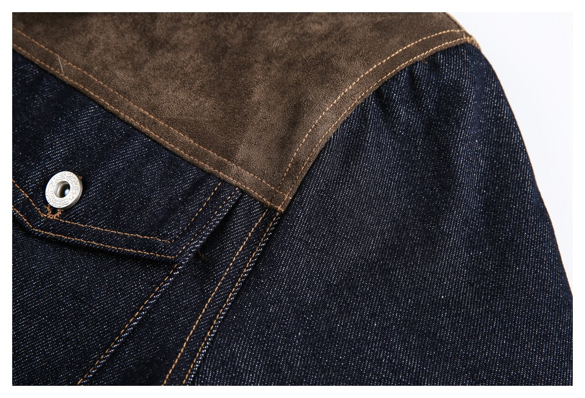 Close-up of a dark indigo denim jacket shoulder and pocket, with a brown panel, tan stitching, and a silver snap.