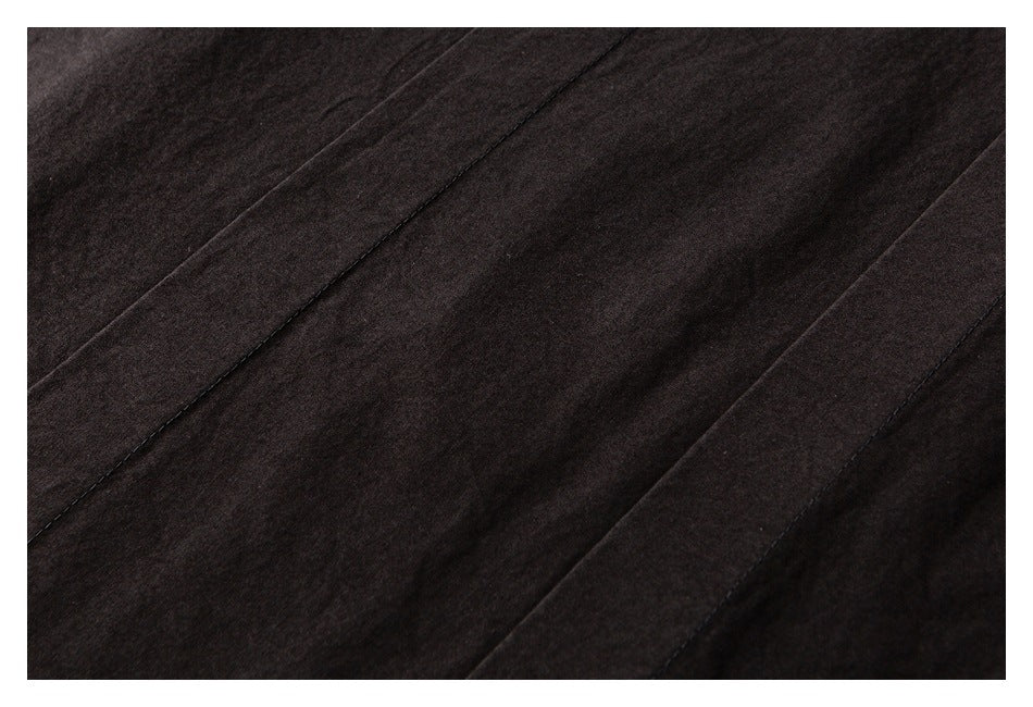 Close-up of dark garment fabric with long stitched seams and panel details.