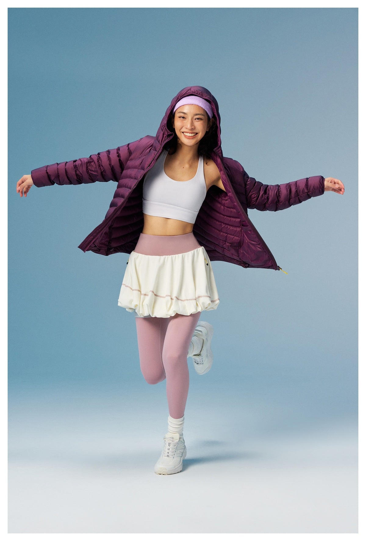 Model shows the plum quilted jacket open, revealing its lining and a white top; the hood is up.